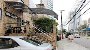 A white car parked on a cobblestone street, a staircase leading to a building with a metal awning, and a row of flowers on the sidewalk. - Hotel Pousada da Praça (Recife)