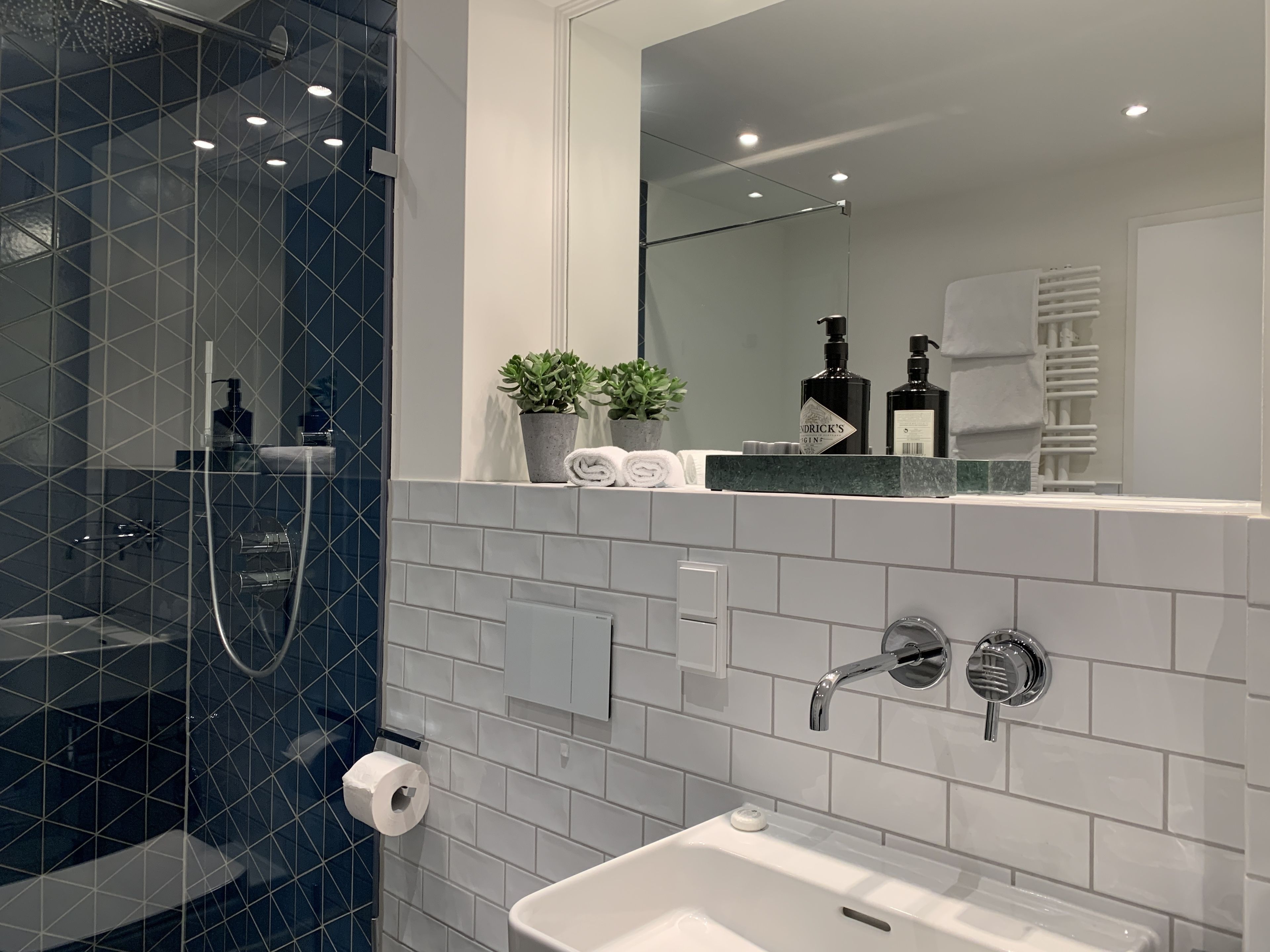 A modern bathroom with a glass shower enclosure, a white sink, and a mirror above the sink.