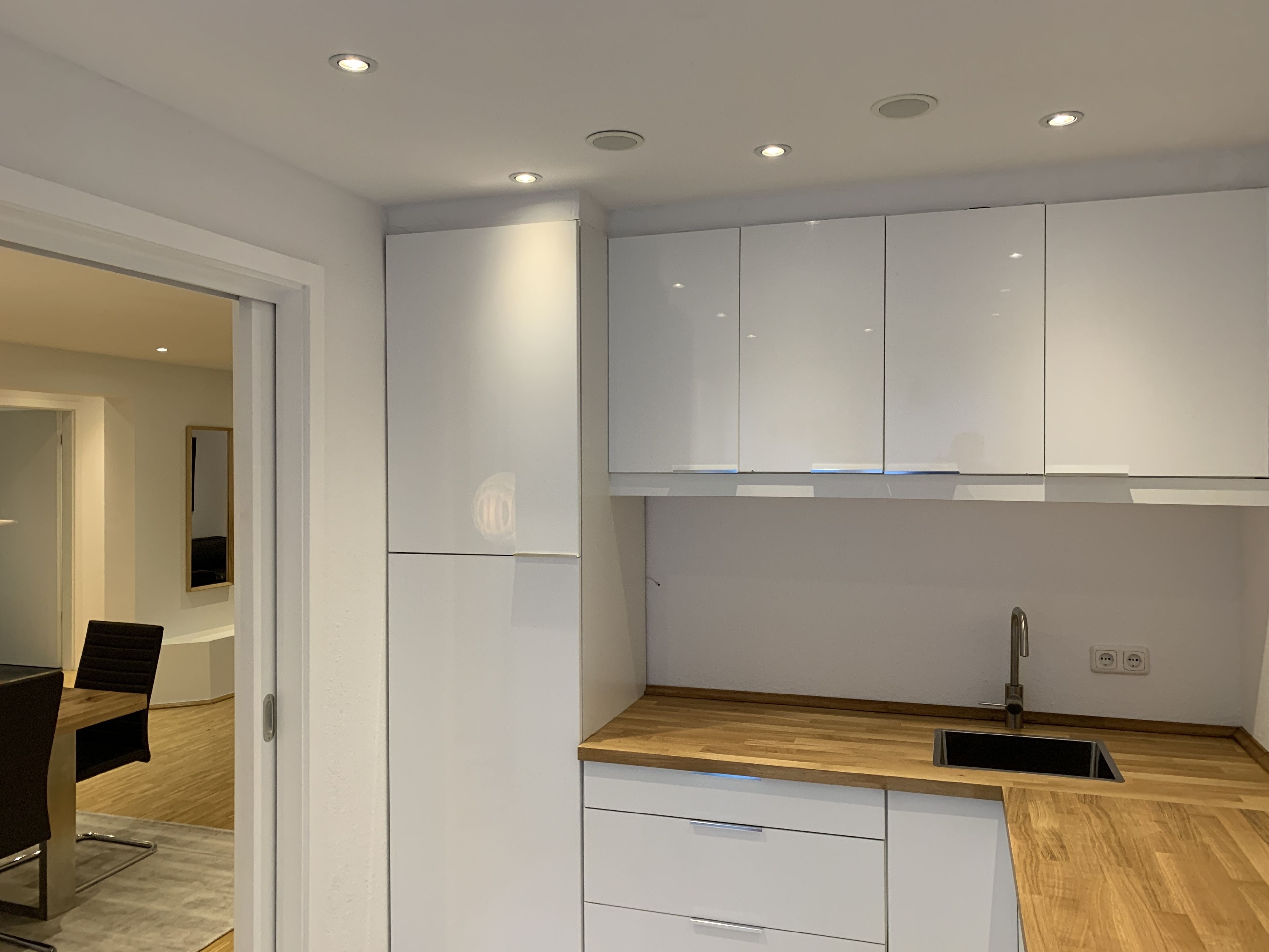 A modern kitchen with white cabinets, a wooden countertop, and a built-in sink.