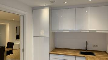 A modern kitchen with white cabinets, a wooden countertop, and a built-in sink.