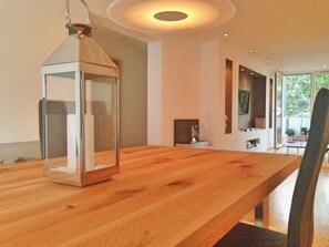 A wooden table with a hanging lantern, a fireplace, and a view of the outdoors. - The Apartment Downtown (Mainz)