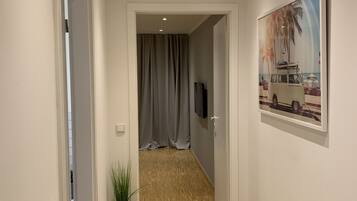 Ein Flur mit Holzboden, einem Bild an der Wand und einer Tür zu einem anderen Raum.