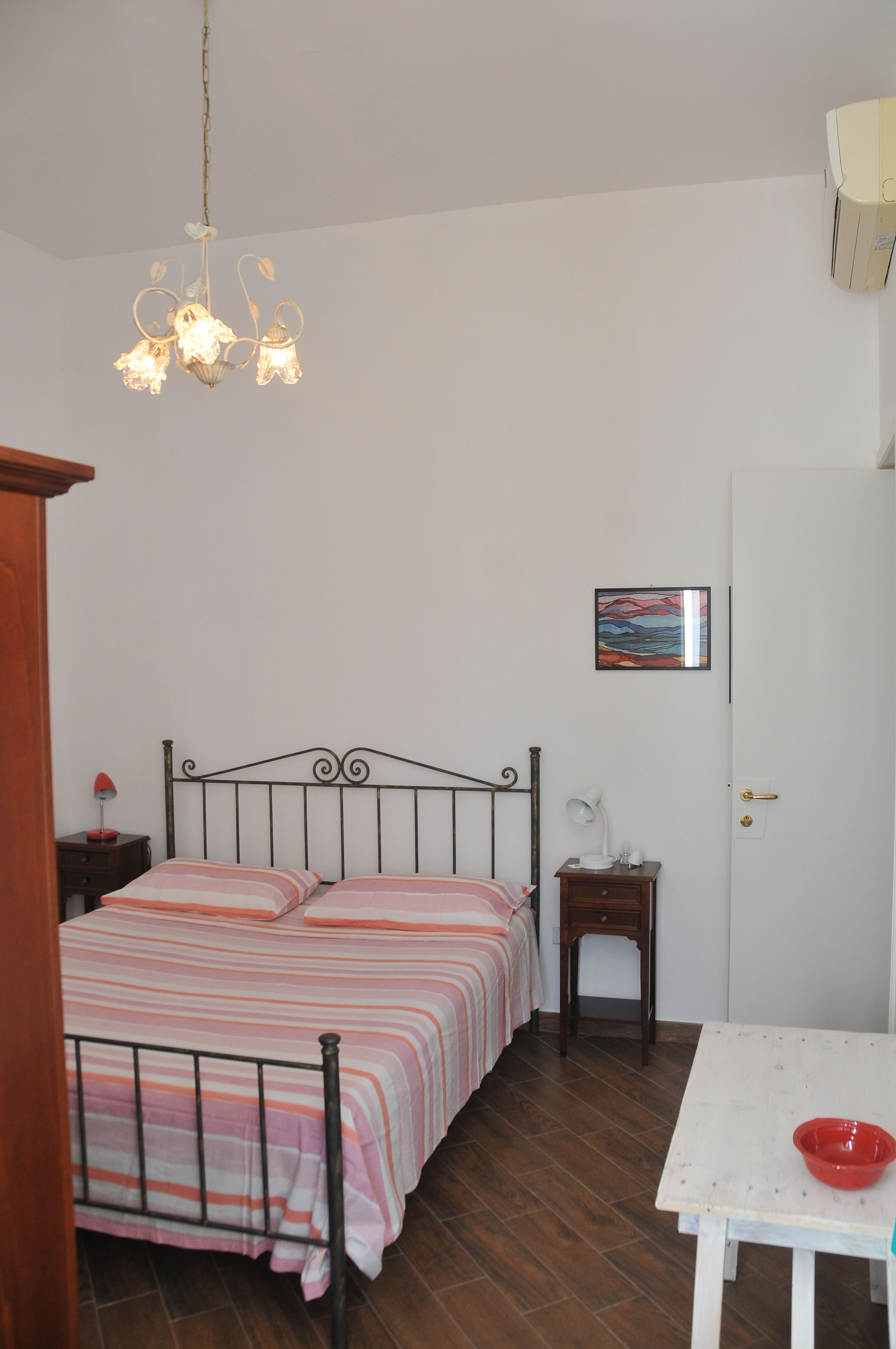 A bedroom with a bed, bedside table, lamp, and a small table with a bowl.