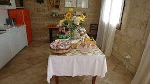 Una mesa de comedor dispuesta con diversos alimentos y un florero con girasoles en una habitación con paredes de piedra rústica.