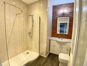 A modern bathroom with a glass-enclosed shower, a white sink, and a toilet. - The Lawns Hotel (Derby)