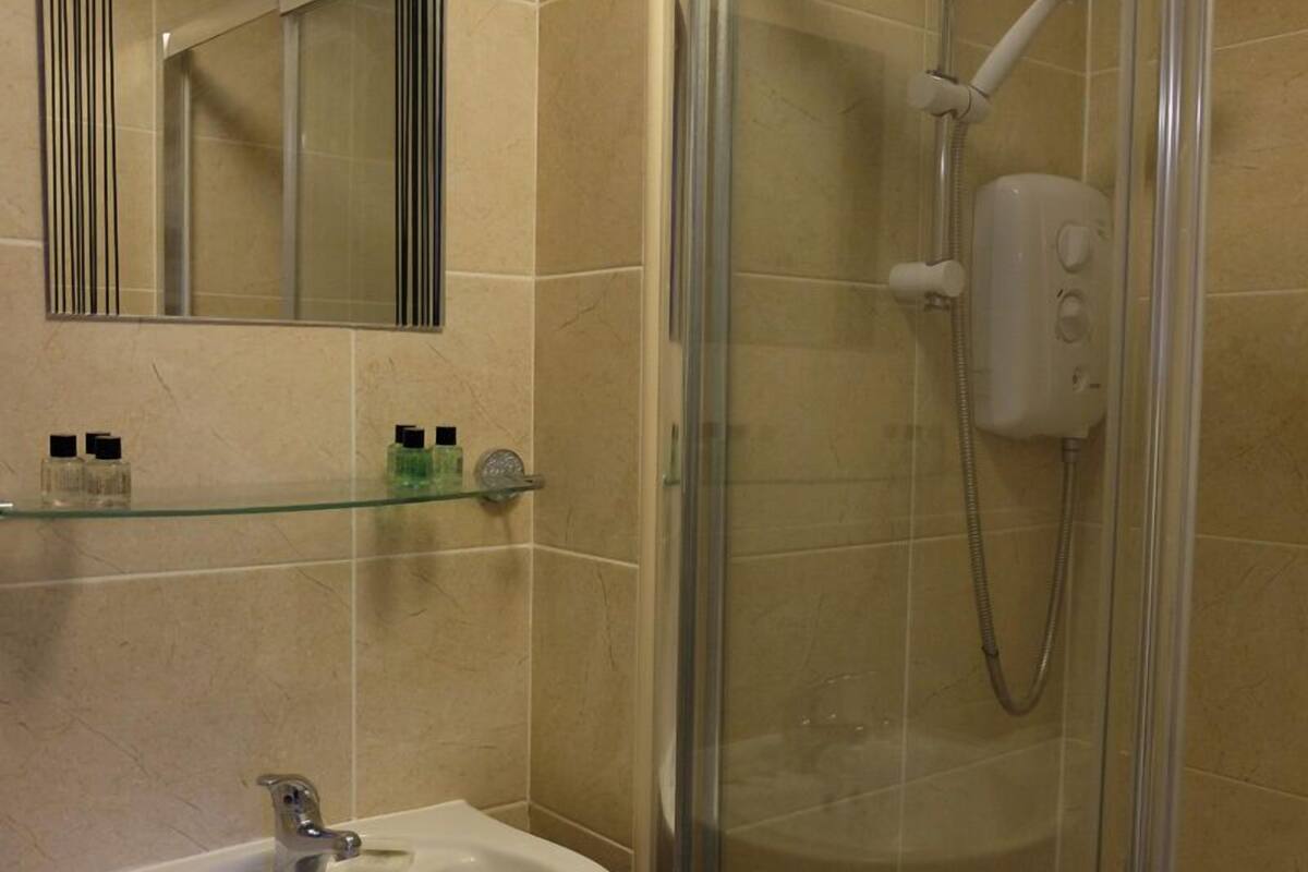 A bathroom with a glass-enclosed shower, a white sink, and a mirror above the sink.