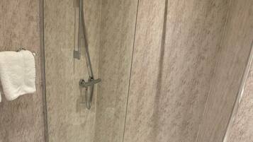 Un baño moderno con ducha envuelta en vidrio, un inodoro blanco y una puerta de vidrio para la ducha.