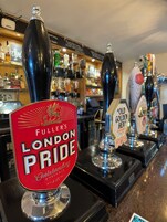 A bar counter with multiple beer taps, including a prominent tap labeled "FULLER'S LONDON PRIDE".