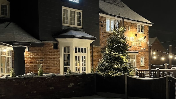 A hotel with a sign reading "The Lawns Hotel" at night, featuring a brick facade and a snow-covered ground. - The Lawns Hotel (Derby)