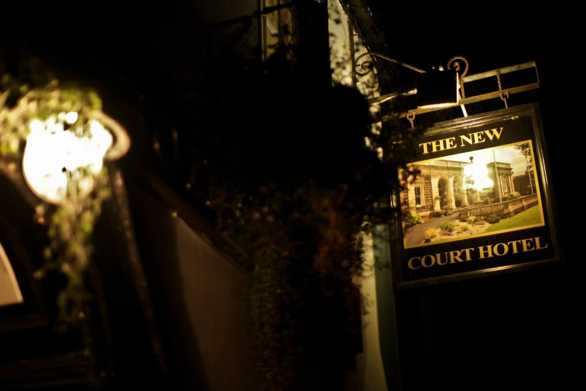 A sign for 'The New Court Hotel' with a photo of a building and the hotel's name.
