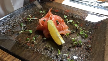 A plate of food with salmon, capers, and a lemon wedge.