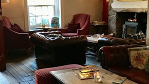 A cozy room with leather sofas, a wooden table, and a fireplace. - The New Court Inn (Usk)