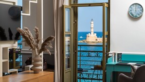 Ein Zimmer mit Blick auf einen Leuchtturm, einer Wanduhr und einer Vase mit Trockenpflanzen auf dem Tisch.