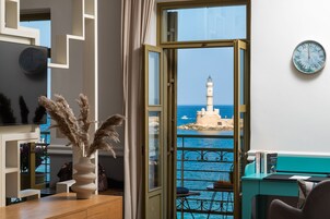 Ένα δωμάτιο με θέα σε έναν φάρο, ένα ρολόι στον τοίχο και ένα βάζο με αποξηραμένα φυτά πάνω στο τραπέζι.
