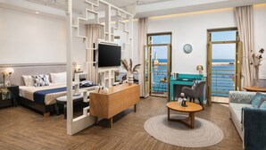 Ein modernes Hotelzimmer mit Bett, Fernseher, Schreibtisch und Meerblick.