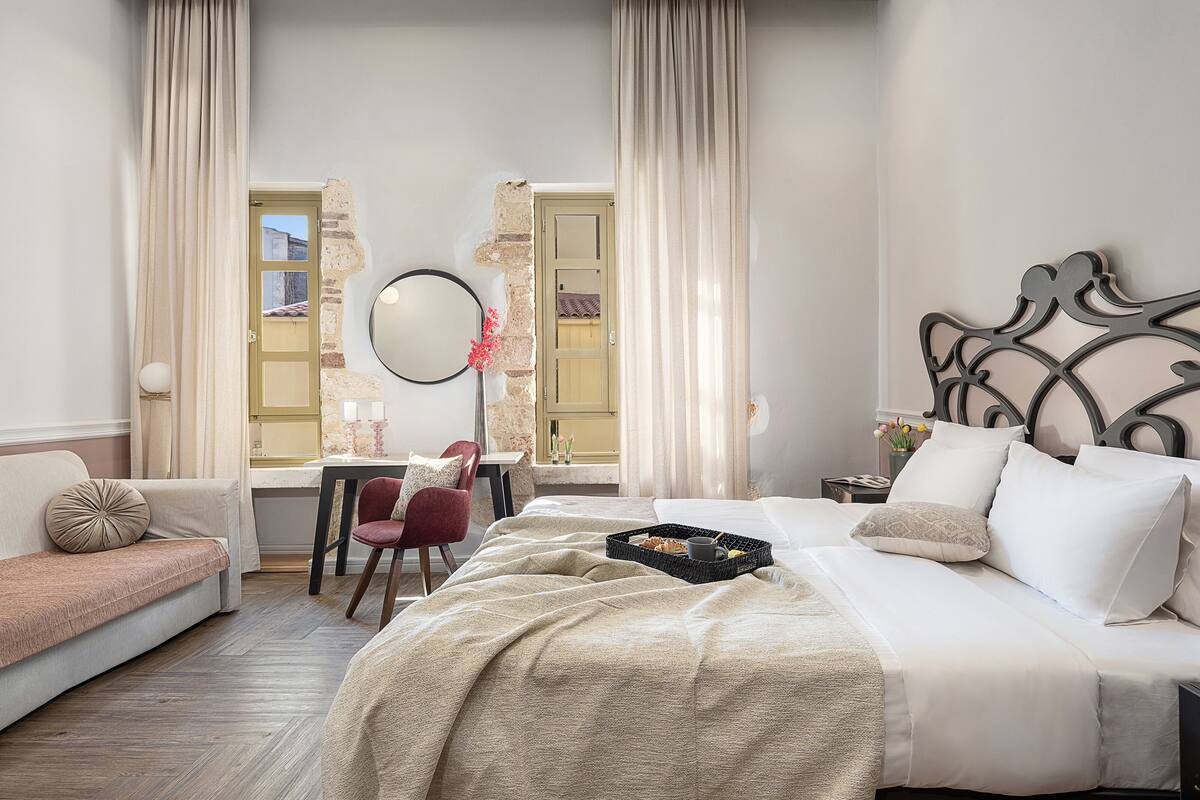 A hotel room with a bed, a desk, a chair, and a window with curtains.