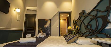 A hotel room with a bed, a flat-screen TV, an air conditioning unit, and a painting on the wall.