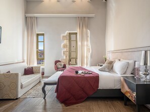 Un dormitorio con cama, mesita de noche, lámpara y vistas al exterior a través de una ventana.
