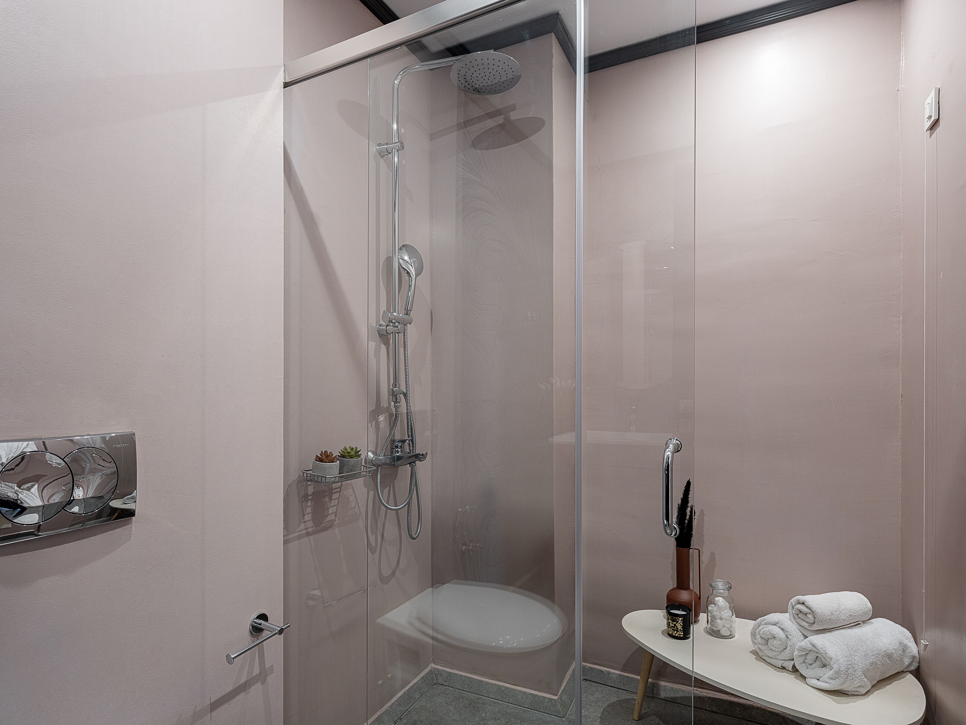 A modern bathroom with a glass-enclosed shower, a toilet, and a vanity with towels.