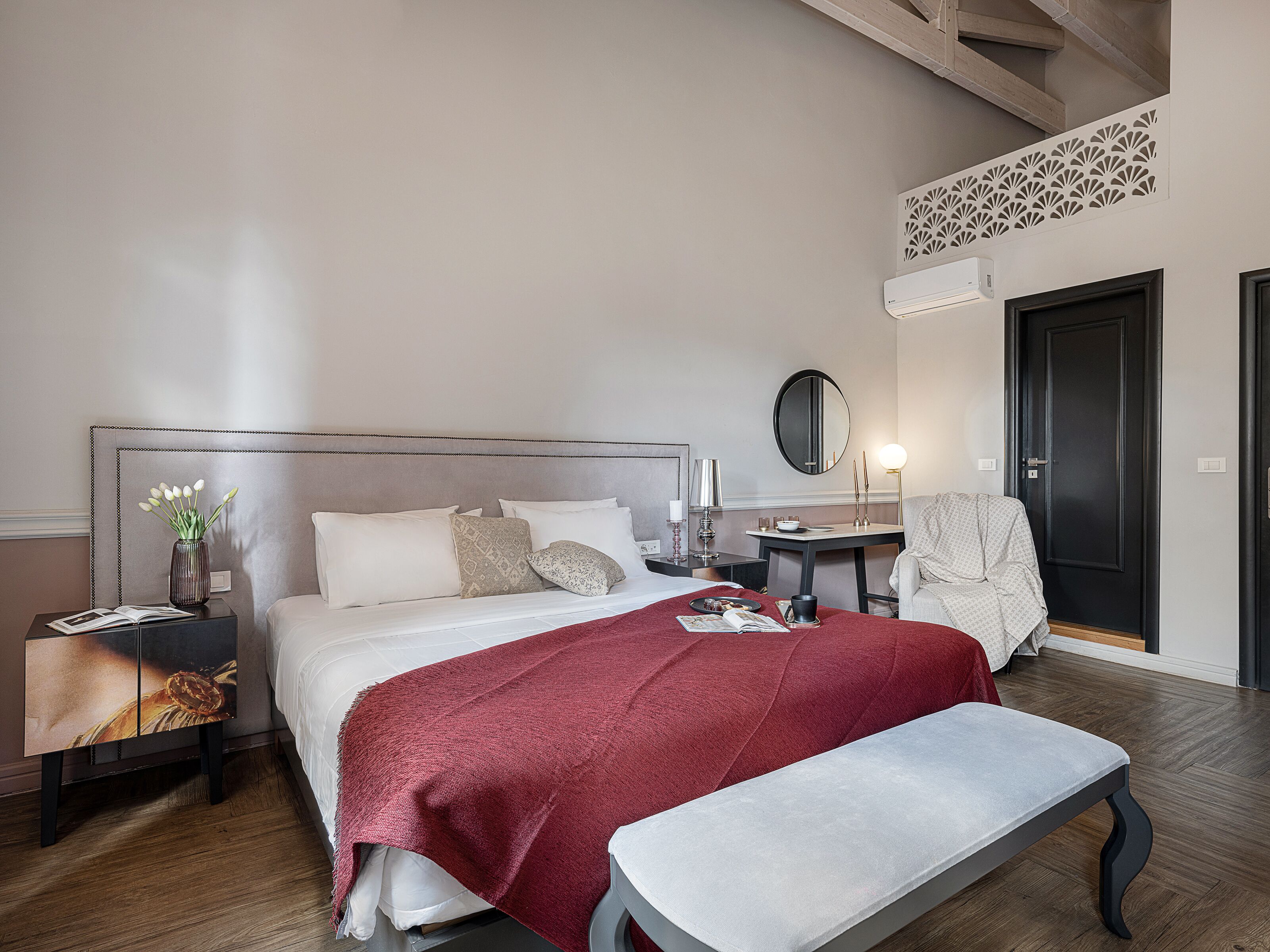 A neatly arranged bedroom with a bed, bedside tables, a chair, and a bench.