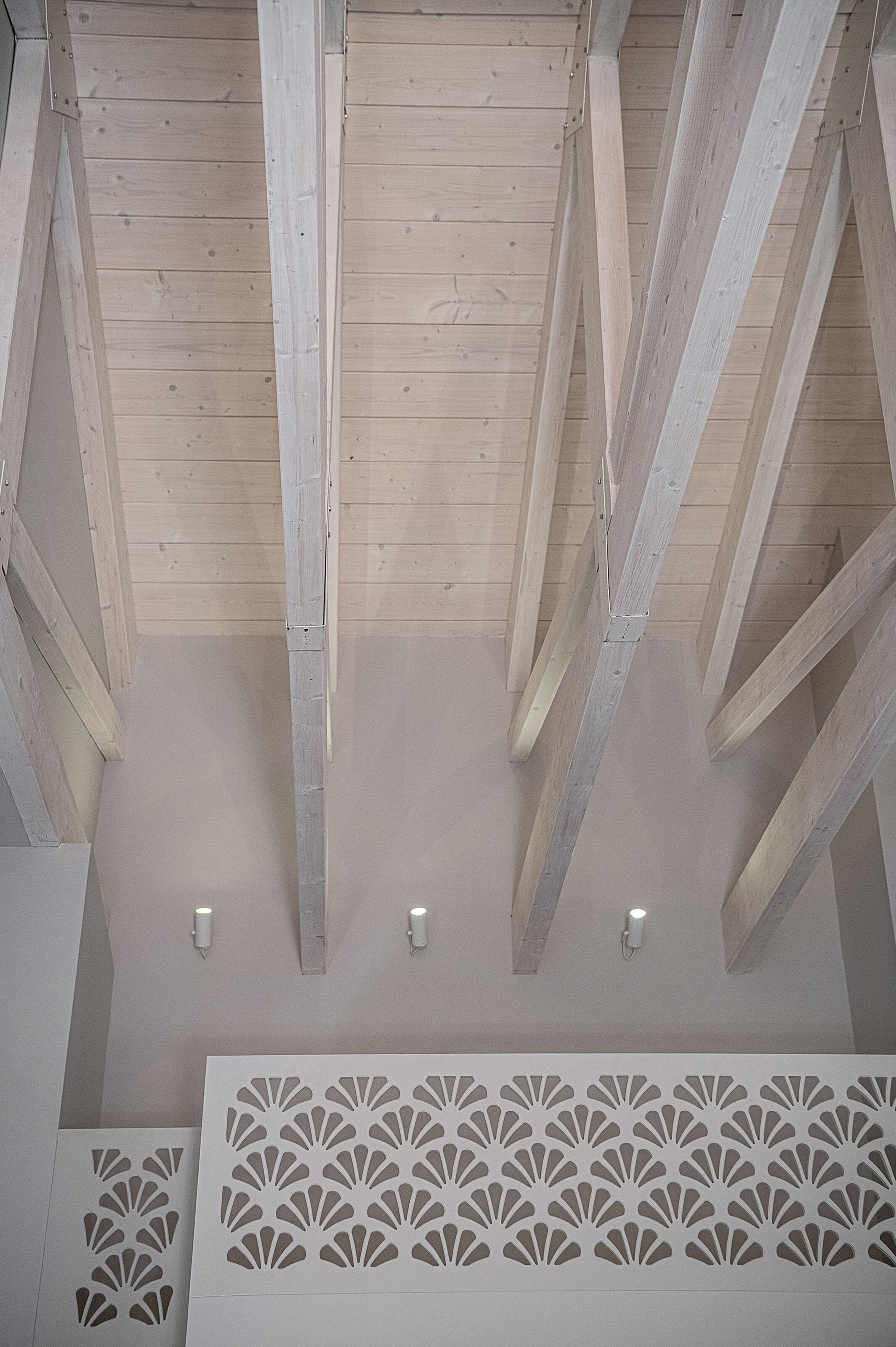 A ceiling with wooden beams and recessed lighting.