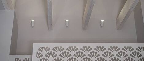 A ceiling with wooden beams and recessed lighting.