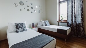 Ett hotellrum med två sängar, en vägg med runda speglar, ett fönster med gardiner och ett litet bord med en lampa.