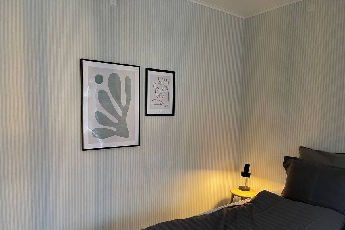 Un dormitorio con una cama, una mesita de noche y dos cuadros en la pared.