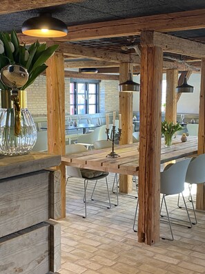 Un comedor rústico con vigas de madera a la vista, una mesa de madera larga y sillas de metal.