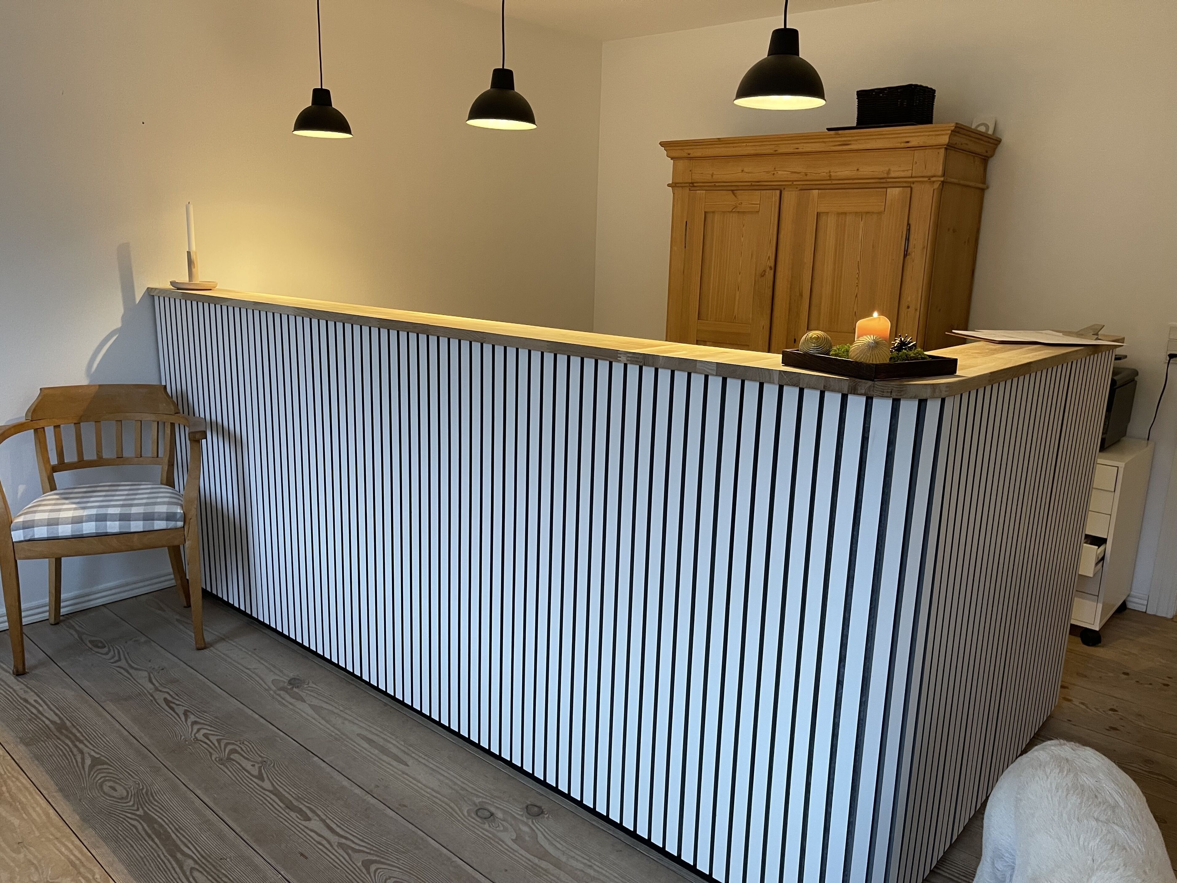 Una cocina con encimera a rayas, armarios de madera, lámparas colgantes y una silla.