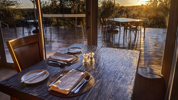 Un espace extérieur aménagé pour les repas, avec des tables et des chaises, une terrasse en bois et des parasols.