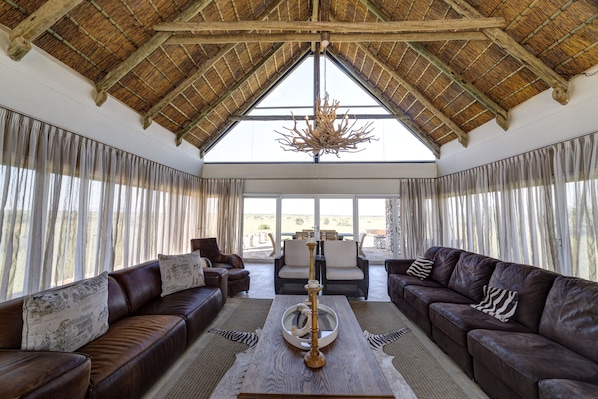 A spacious living area with leather sofas, a wooden coffee table, and a chandelier.