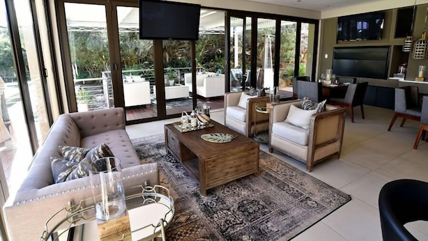 Amplia sala de estar con un televisor grande, asientos cómodos y vistas al exterior.
