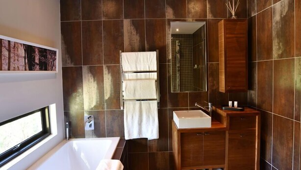 Une salle de bain moderne avec une grande baignoire, un meuble-lavabo et un miroir.