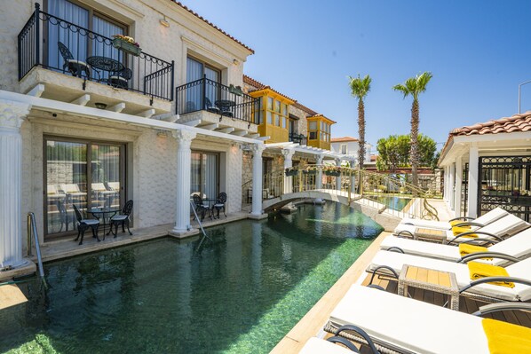 A pool area with lounge chairs and a bridge. - Hotel De Gold Alacati (Cesme)
