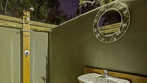 A bathroom with a wooden door, a sink, and a mirror with a floral design. - Neuras Wine & Wildlife Estate (Sesriem)