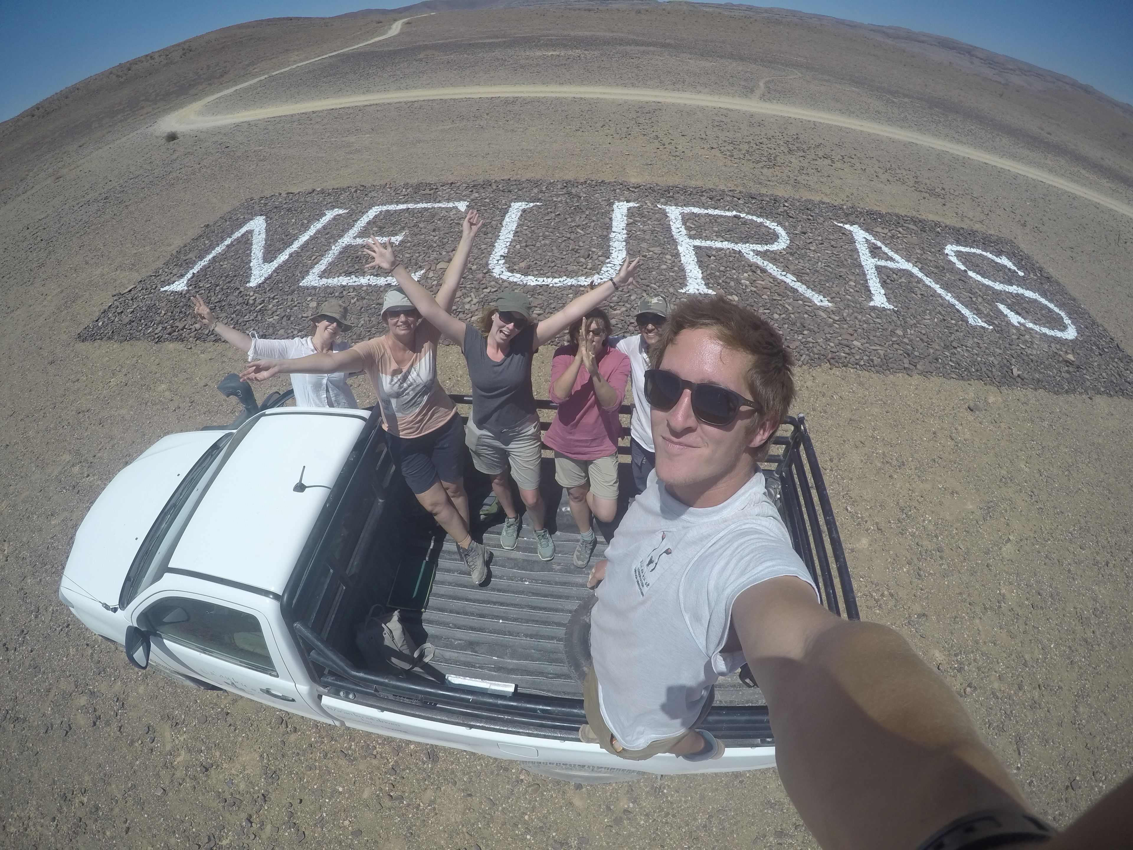 A group of people standing on a rocky terrain with the word "NEJURAS" painted on the ground.