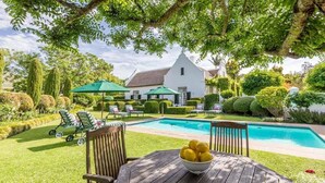 Una piscina al aire libre, sombrillas, sillones reclinables de piscina