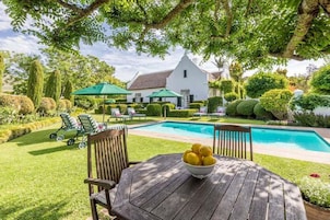 Una piscina al aire libre, sombrillas, sillones reclinables de piscina