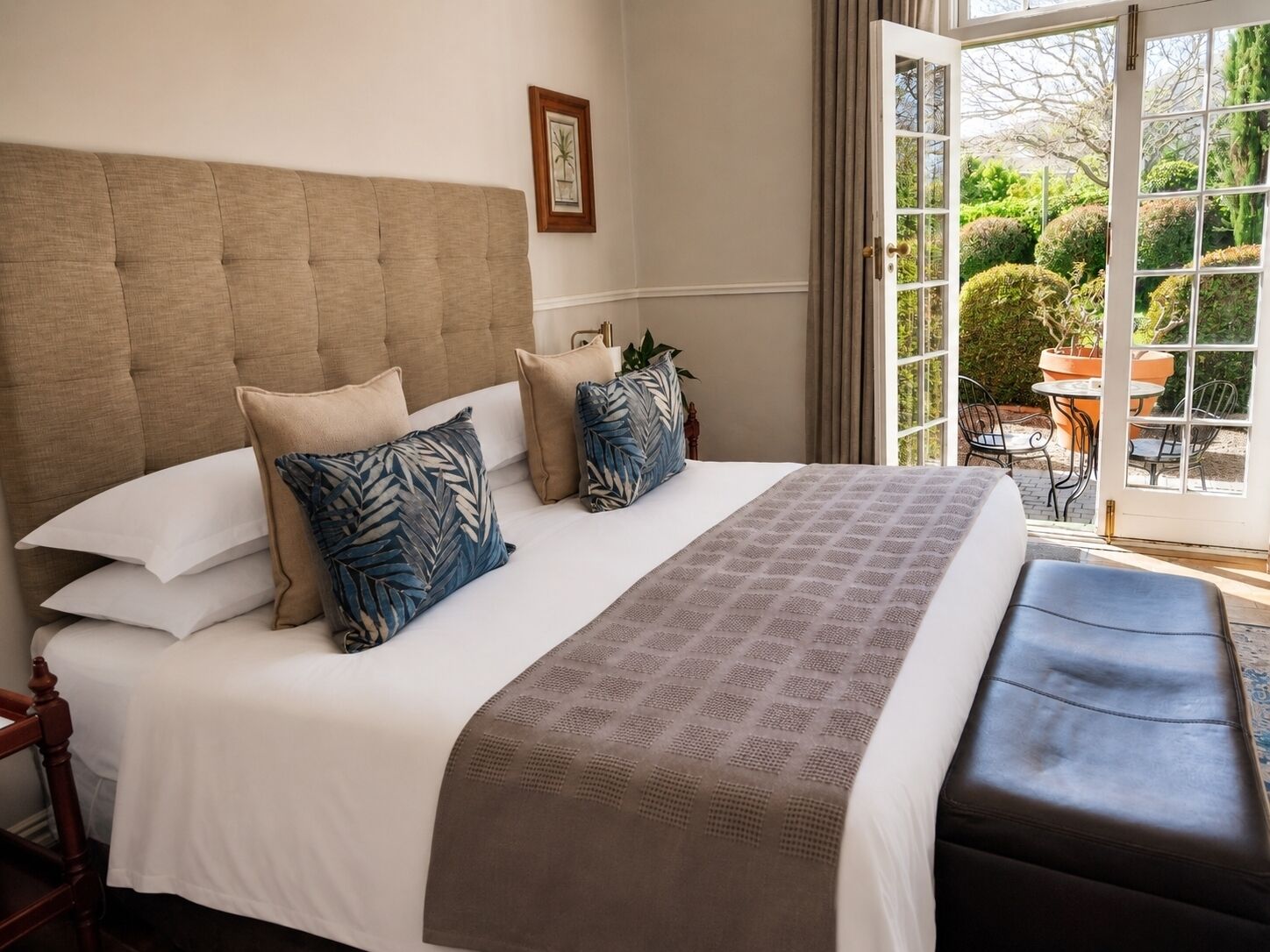 Une chambre à coucher avec un grand lit, une tête de lit et une vue sur l’extérieur grâce à une porte vitrée.