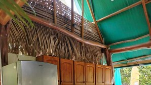 A compact kitchen with a refrigerator, stove, and wooden cabinets. - Aloha Surf Nosara (Nosara)