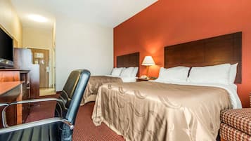 Habitación de hotel con dos camas, un escritorio, una silla y una lámpara.