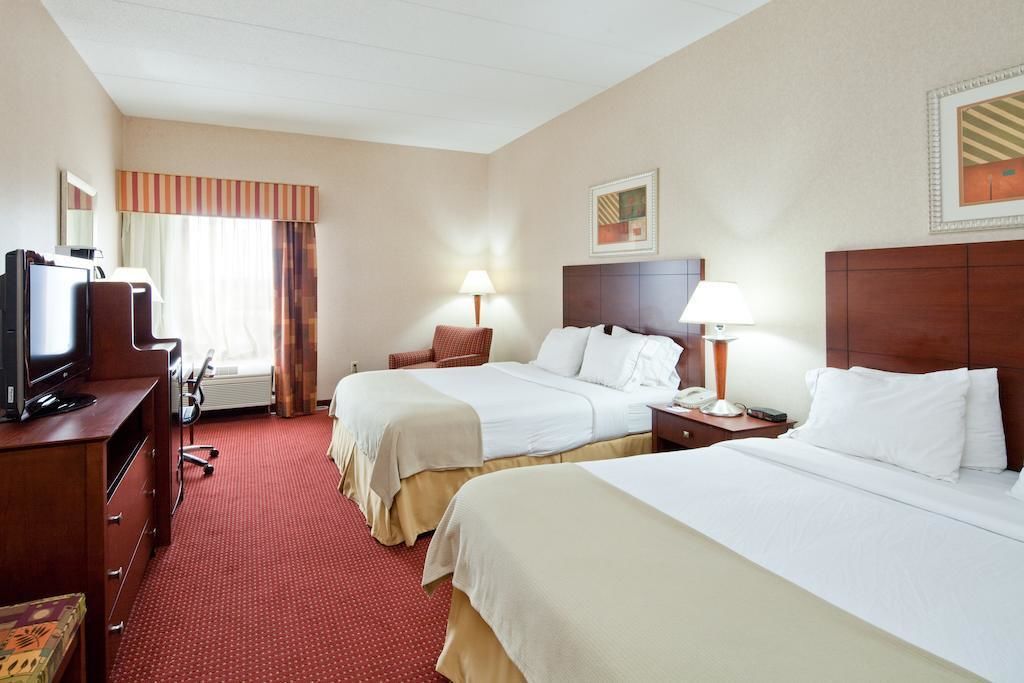 A hotel room with two beds, a TV, a desk, and a chair.