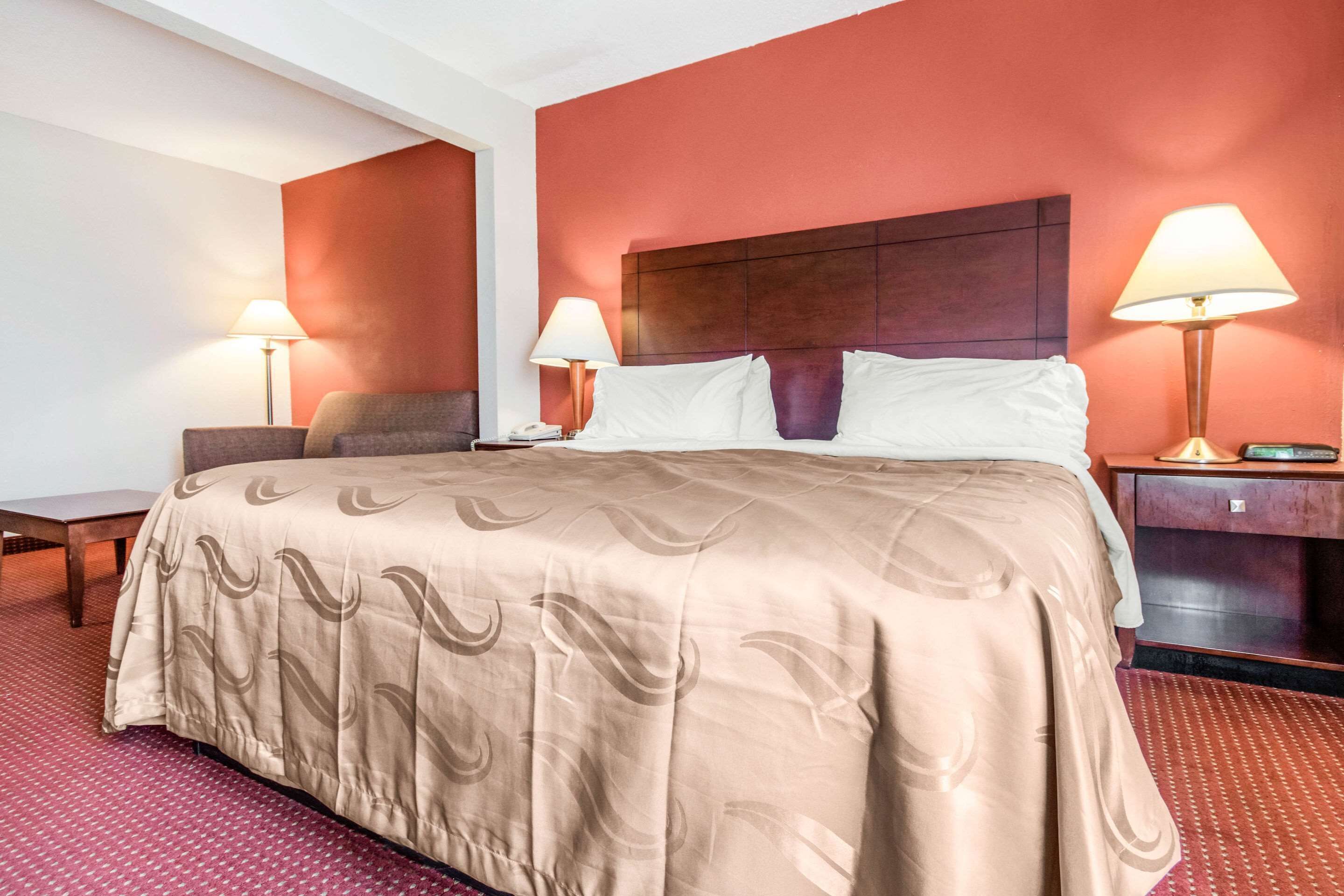 Una habitación de hotel con una cama grande, dos mesitas de noche y dos lámparas.