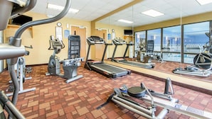 Un gimnasio con cintas de correr, máquinas elípticas y equipo de pesas.
