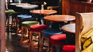 A restaurant interior with wooden tables and chairs, potted plants, and a brick wall. - Camden Enterprise Hotel & Pub (London)