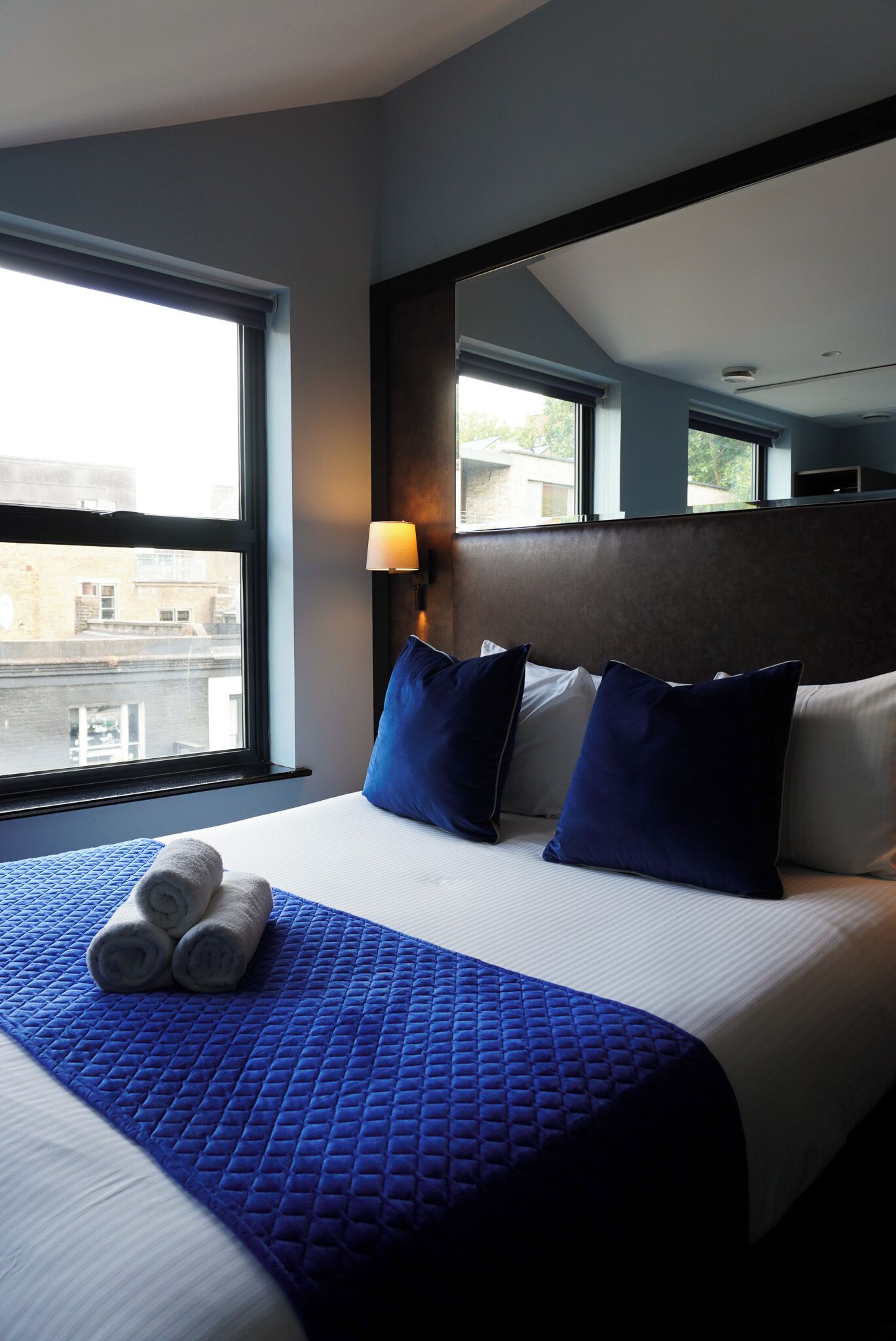 A hotel room with a large bed, a headboard, and a window.