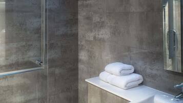 A modern bathroom with a glass shower enclosure, a white toilet, and a vanity with a mirror.