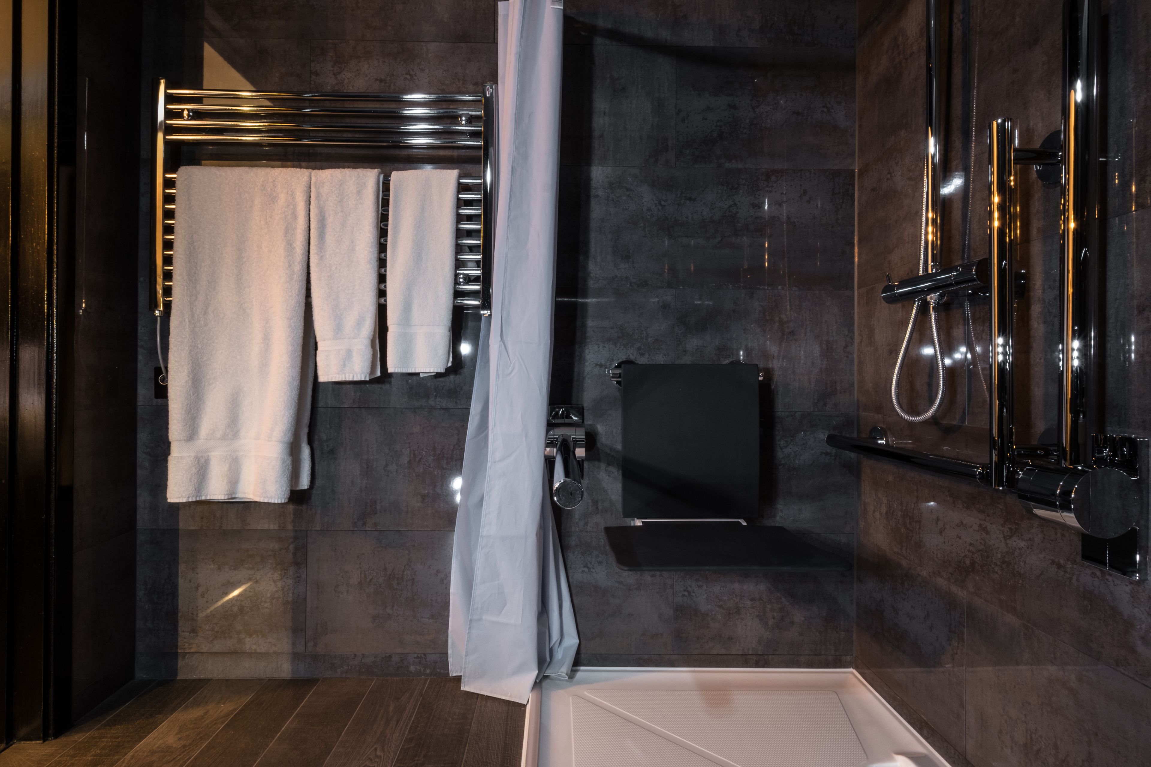 Un baño moderno con cabina de ducha de vidrio, toallero empotrado y tocador negro.
