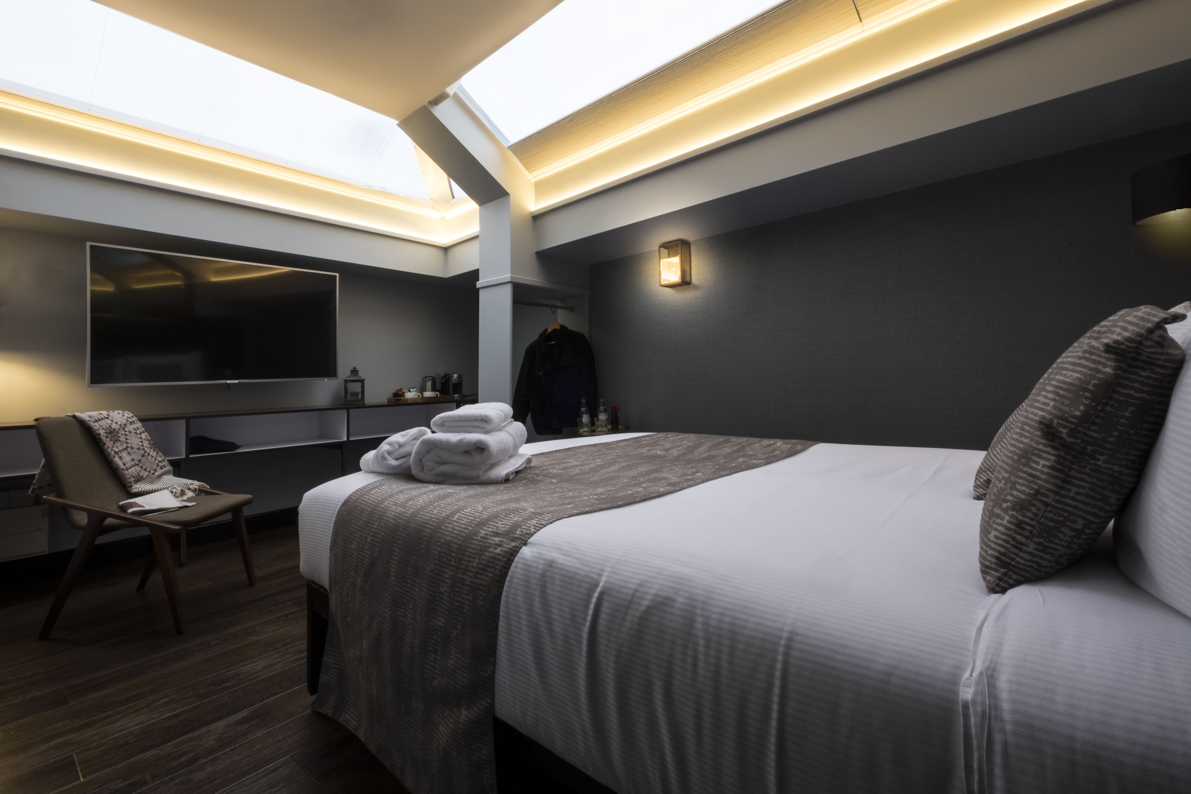 A modern hotel room with a large bed, a flat-screen TV, a desk, and a chair.